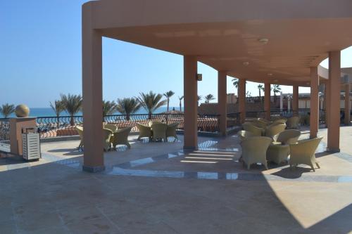 a covered patio with chairs and the ocean in the background at Vai by Romance Hotel & Aqua Park in Ain Sokhna