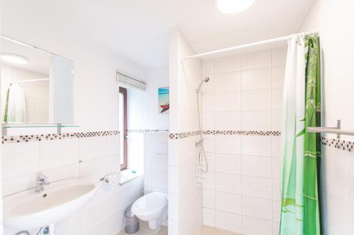 a white bathroom with a sink and a toilet at Ferienwohnung Hummelhus Elmenhorst in Elmenhorst