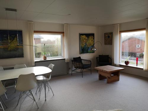 ein Wohnzimmer mit einem Tisch, Stühlen und Fenstern in der Unterkunft Værelse som dobbelt el. enkelt, Engen 5, 7770 Vestervig in Vestervig