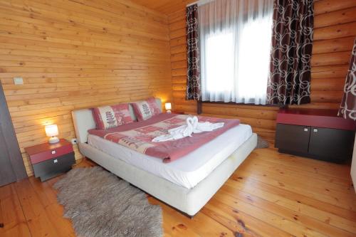 a bedroom with a bed with wooden walls and a window at Hotel Panorama in Panichishte