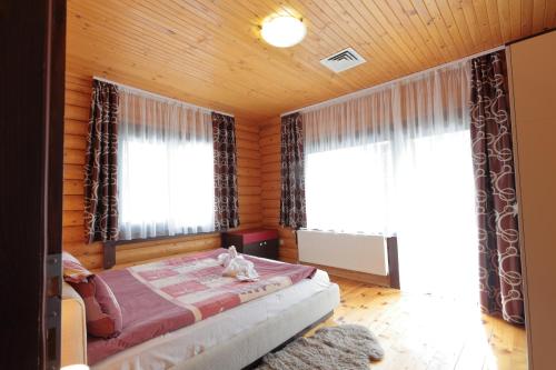 a bedroom with a bed and two windows at Hotel Panorama in Panichishte