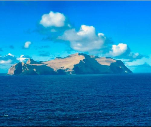 a mountain in the middle of a body of water at The Atlantic view guest house, Sandavagur, Faroe Islands in Sandavágur