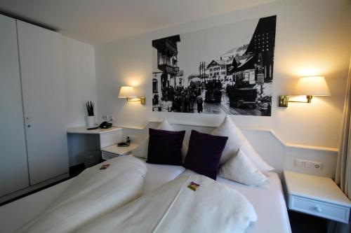 a bedroom with a white bed with two pillows at Hotel-Garni Fels in Riezlern