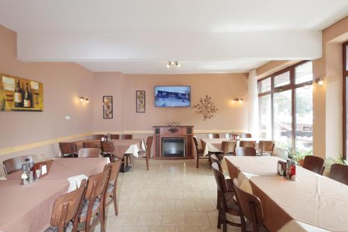 a restaurant with tables and chairs and a tv on the wall at Hotel Panorama in Panichishte