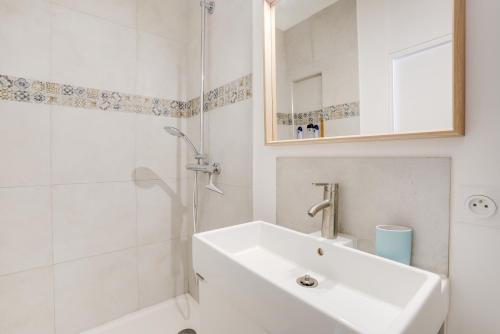 y baño blanco con lavabo y ducha. en Charme et Design à Proximité du Château, en Fontainebleau