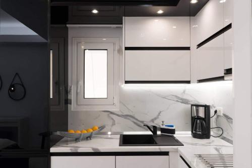 una cucina con armadi bianchi, lavandino e finestra di Affordable luxury studio close to Ampelokipi metro ad Atene