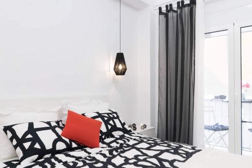 una camera da letto con un letto bianco e nero con un cuscino rosso di Affordable luxury studio close to Ampelokipi metro ad Atene