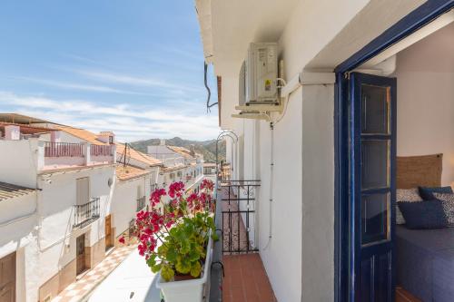 a balcony with flowers on a white building at Casa Randonneur, traditional townhouse in Álora. in Alora