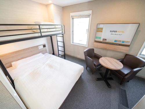 a room with a bunk bed and a desk and chair at Super Hotel Higashi-Maizuru in Maizuru