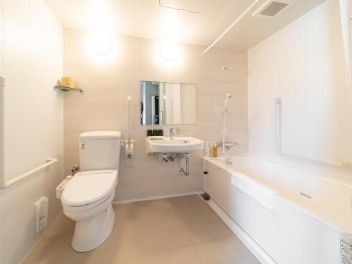 a white bathroom with a toilet and a sink at Super Hotel Higashi-Maizuru in Maizuru