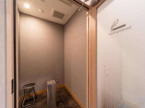 a walk in shower in a room with a stool at Super Hotel Higashi-Maizuru in Maizuru