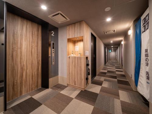 a hallway with wooden doors and a checkered floor at Super Hotel Higashi-Maizuru in Maizuru