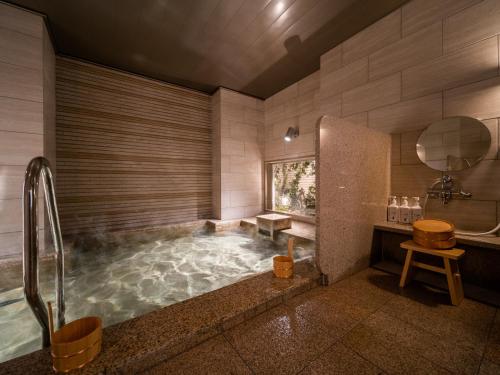 a large bathroom with a tub with water in it at Super Hotel Higashi-Maizuru in Maizuru