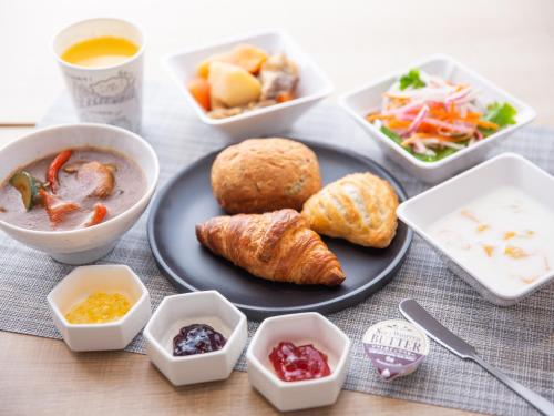 a table with a plate of food and bowls of food at Super Hotel Higashi-Maizuru in Maizuru