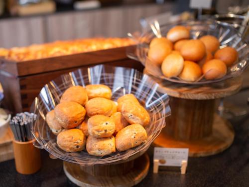 a table with baskets of bread and baskets of food at Super Hotel Higashi-Maizuru in Maizuru
