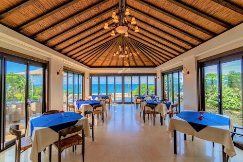 a dining room with tables and chairs and the ocean at Villabu Resort in Miyako-jima