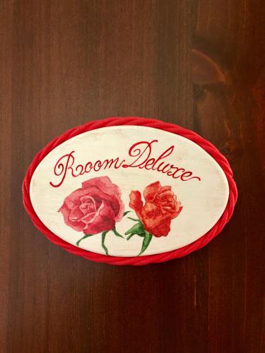 a sign with roses on it on a wooden table at B&B Roomantic & Piscina Idromassaggio in Cefalù
