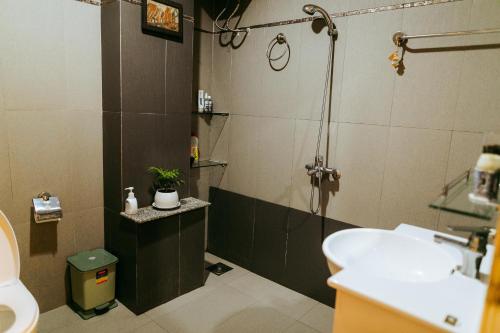 ein Bad mit einer Dusche und einem Waschbecken in der Unterkunft Kota's House Homestay in Hue