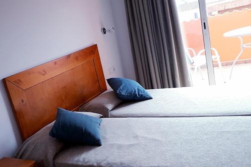 a bedroom with two beds with blue pillows and a window at PALMA in Malgrat de Mar