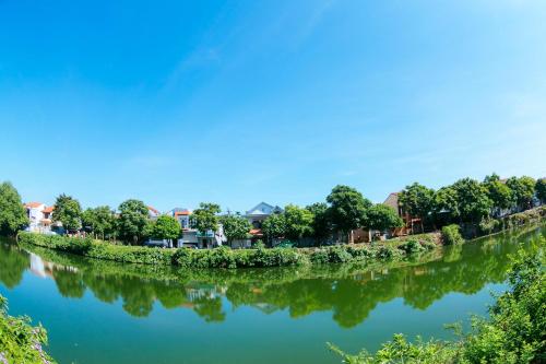 a river with houses and trees in the background at Kota's House Homestay in Hue