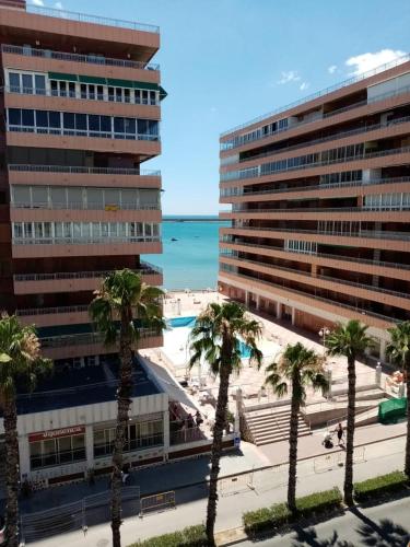 uma vista para um hotel e uma praia com palmeiras em APARTAMENTO con BUENA VISTA em Torrevieja