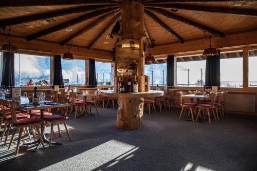 a dining room with tables and chairs and windows at Berggasthaus First - Only Accessible by Cable Car in Grindelwald