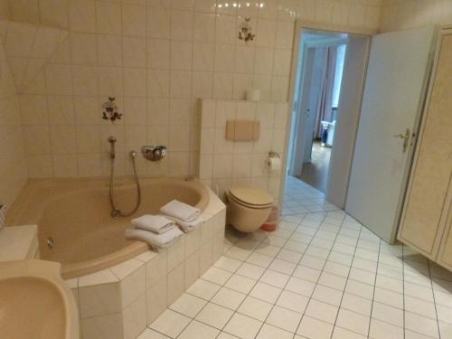 a bathroom with a tub and a toilet and a sink at Winzergasthof zum Kellerstübchen in Mehring