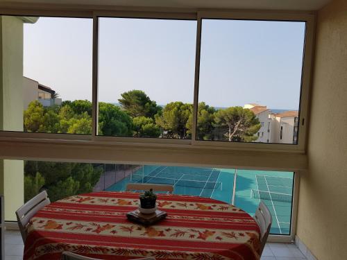 d'une grande fenêtre avec une table et une vue sur la piscine. dans l'établissement APPT 1 CHAMBRE QUARTIER DES PLAGES, à Sète