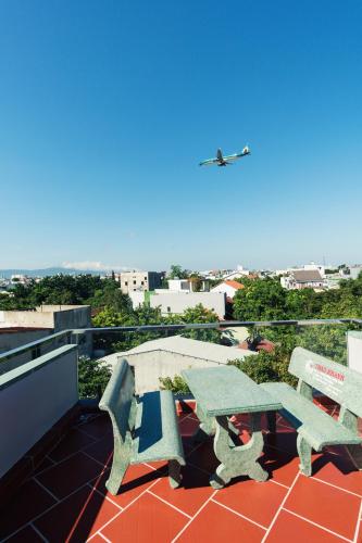 a picnic table and bench on a roof with an airplane at Nhà của Elly in Da Nang