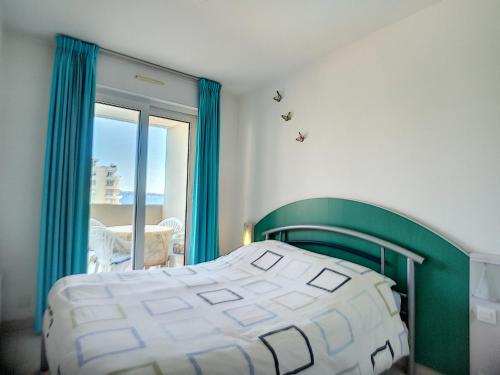 una camera con un letto verde e bianco e una finestra di Antibes les Pins 2 Pièces vue mer piscine parking a Antibes