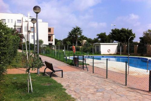 una recinzione accanto a una piscina con panchina di Chill out ground floor apartm +private garden+WIFI a Retamar