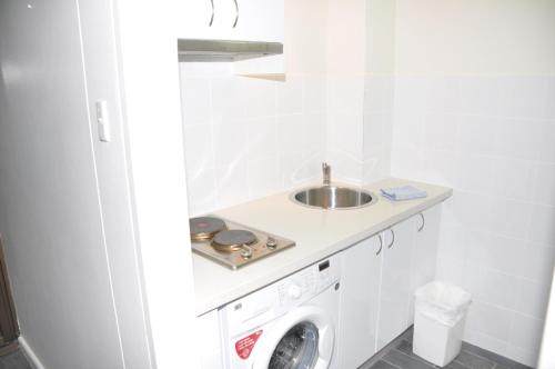 La salle de bains est pourvue d'un lavabo et d'un lave-linge. dans l'établissement Accommodation Sydney Studio with balcony apartment, à Sydney
