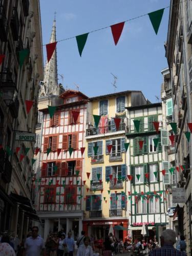 a group of buildings on a street with people and flags at Chalet Zure Ondoan - SPA et piscine chauffée in Labenne