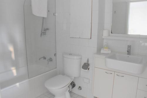 Baño blanco con aseo y lavamanos en Accommodation Sydney City Centre - Hyde Park Plaza Park View College Street Studio Apartment, en Sídney