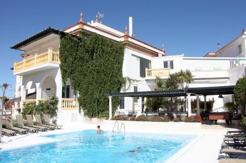 Ein Mann, der in einem Pool vor einem Gebäude schwimmt. in der Unterkunft Al Sur de Chipiona in Chipiona