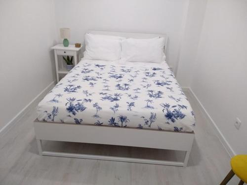 a bed with a blue and white blanket on it at Apartamentos Areia e Mar Sul in Vila Praia de Âncora