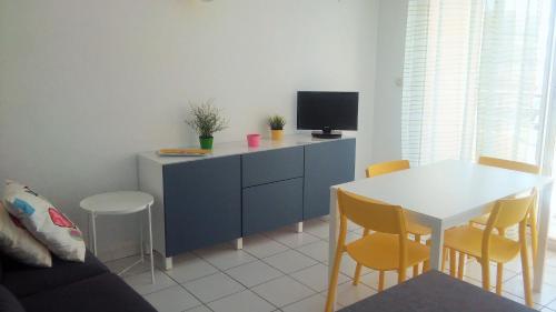 un salon avec un meuble bleu et une table avec des chaises dans l'établissement 1 CHAMBRE, VUE MER, ACCES DIRECT PLAGE, à Sète