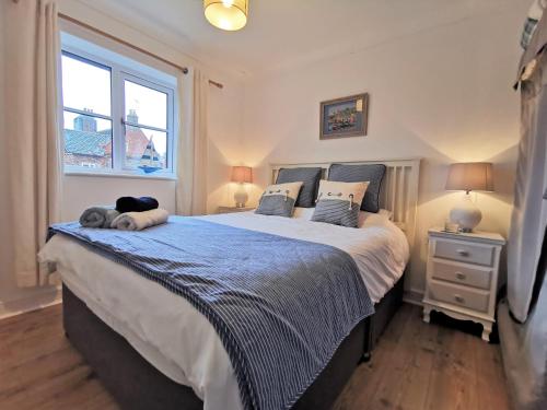 a bedroom with a large bed and a window at AnchorageWells Harbour Apartment in Wells next the Sea