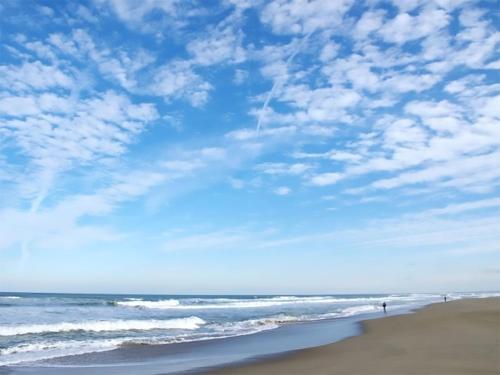 a person standing on a beach with the ocean at Tabino Hotel Kashima in Kamisu