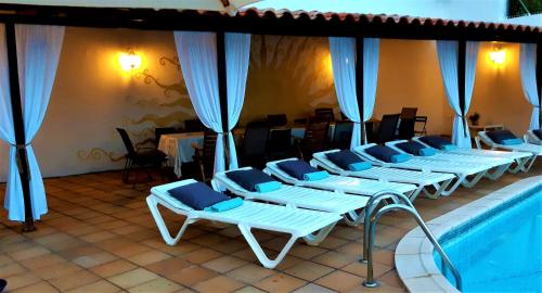 a row of white lounge chairs next to a swimming pool at Ashram Villa Sunshine in Sitges