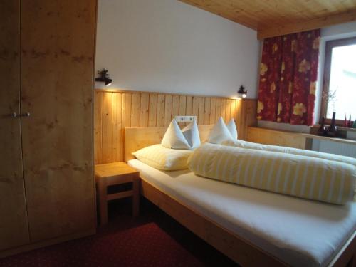 een slaapkamer met een bed met witte kussens en een raam bij Appartements Birkenhof in Lech am Arlberg