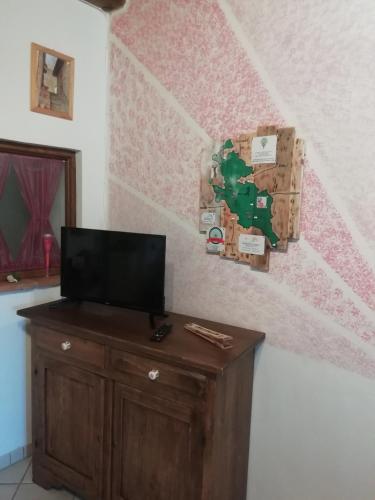 a room with a tv on a dresser and a wall at La Casina in Stia