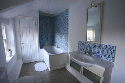 a bathroom with a sink and a tub and a mirror at Totters townhouse in Caernarfon