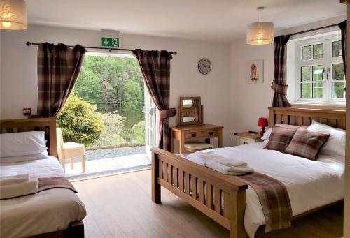 a bedroom with two beds and a large window at Penbont House in Rhayader