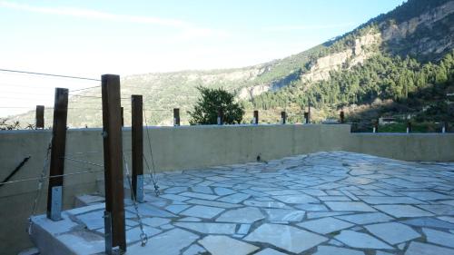 a stone patio with a wall and mountains in the background at The old olive mill house in Aegae