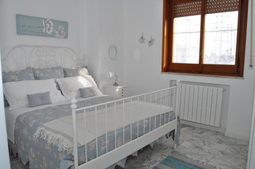 a white bedroom with a bed and a window at I Citri in Taranto