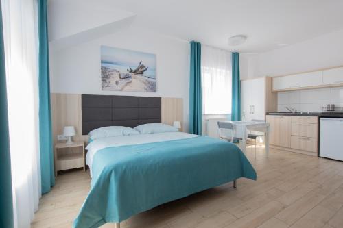 a bedroom with a large bed and a kitchen at Villa Blanca in Grzybowo