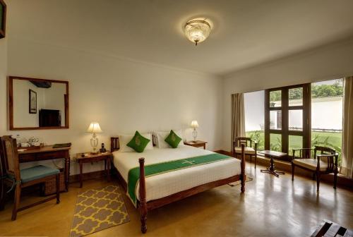 a bedroom with a bed and a desk and a mirror at Saraca Hotel Lucknow in Lucknow