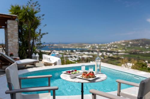 a table with a plate of food next to a pool at Villa Haritomeni in Parikia