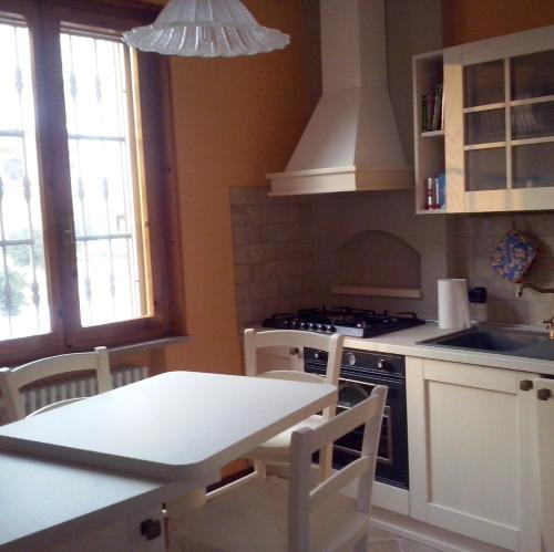 una cocina con electrodomésticos blancos, mesa y sillas en Soggiorno in Relax en Correggioverde